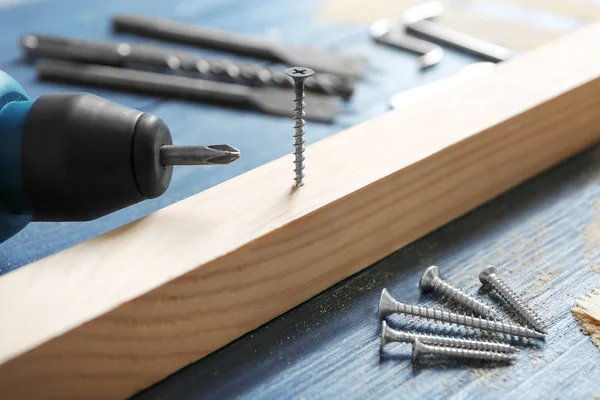 Wooden bar with screw nails and drill — Stock Photo, Image