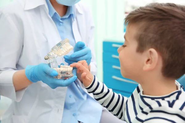 Tandläkare som visar plast käken till pojke — Stockfoto