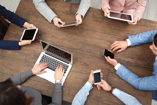 People sitting at table and using digital devices, top view