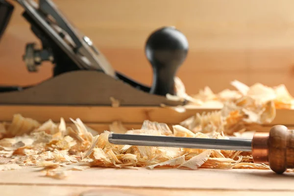 Beitel en zag stof op houten tafel in timmerman werkplaats, close-up — Stockfoto