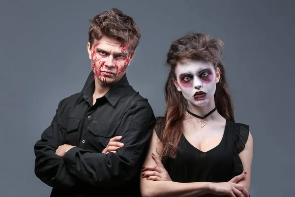 Jovem e mulher com maquiagem de Halloween em fundo cinza — Fotografia de Stock