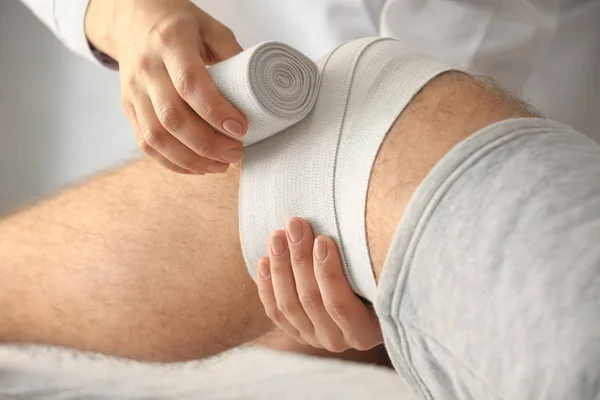 Médico aplicando bandagem na perna do paciente na clínica, close-up — Fotografia de Stock
