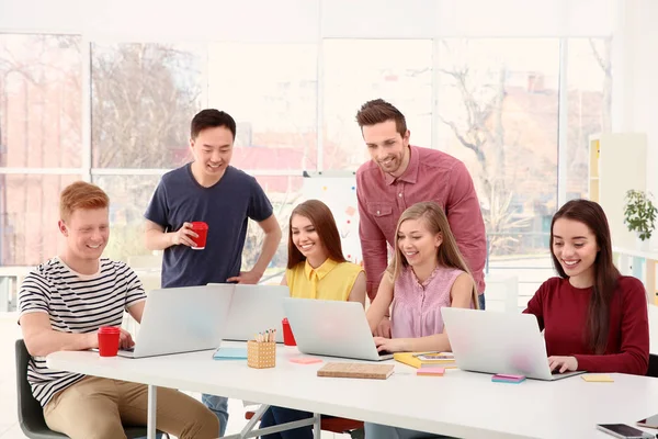 Young people working with laptops in office