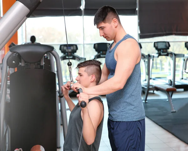 Dad and son training with cable-pull machine in modern gym