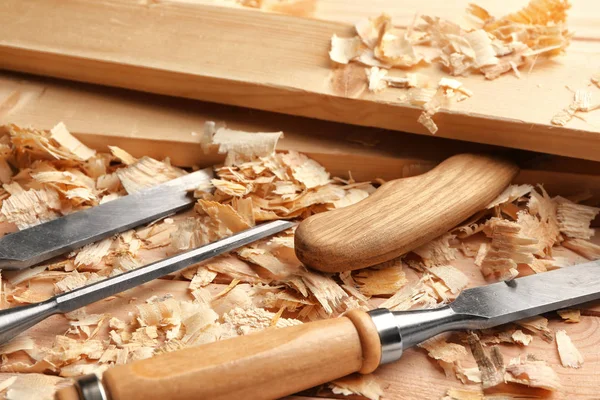 Timmerman gereedschap, planken en zag stof op houten tafel in werkplaats, close-up — Stockfoto