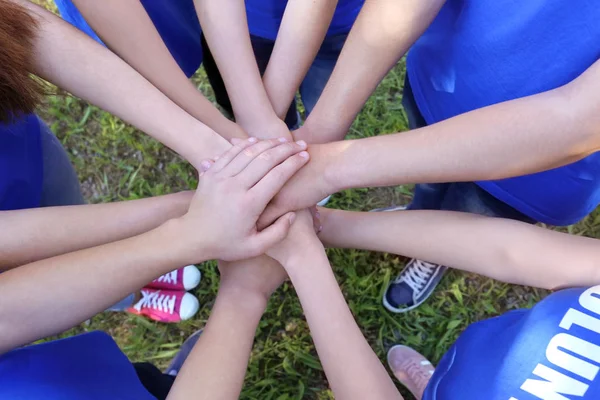 Jóvenes poniendo las manos juntas al aire libre. Concepto de voluntario —  Fotos de Stock