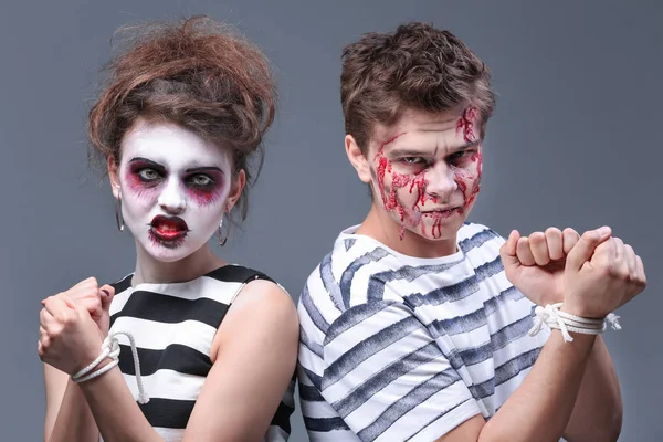 Ung man och kvinna med Halloween smink och bundet händer på grå bakgrund — Stockfoto