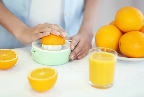 Женские руки делают апельсиновый сок на кухне — стоковое фото