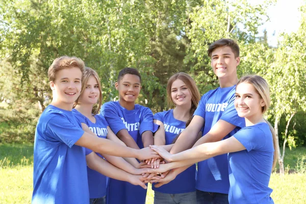 Jóvenes poniendo las manos juntas al aire libre. Concepto de voluntario — Foto de Stock