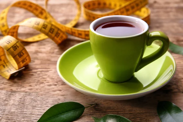 Чашка чая и измерительная лента на деревянном фоне — стоковое фото