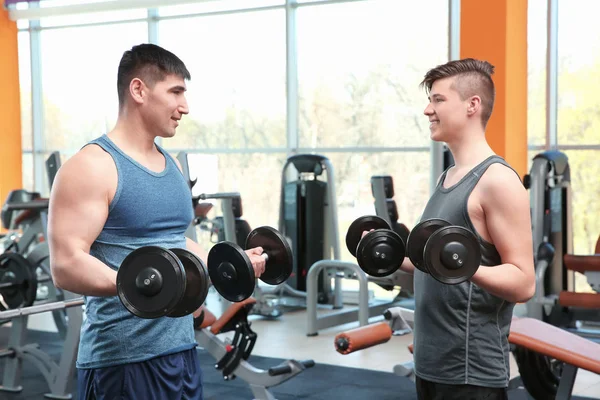 Papa et fils s'entraînent avec des haltères dans la salle de gym moderne — Photo