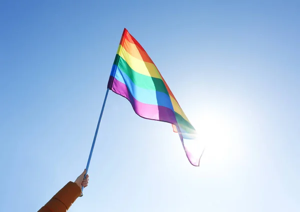 Γυναίκα που κρατά γκέι σημαία σε φόντο μπλε του ουρανού. Έννοια της σεξουαλικής μειονότητας — Φωτογραφία Αρχείου