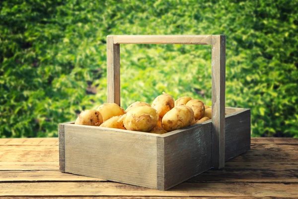 木製テーブルの上の箱で新鮮なジャガイモ — ストック写真