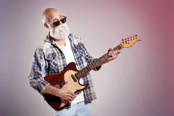 Senior man met gitaar op grijs muur achtergrond — Stockfoto