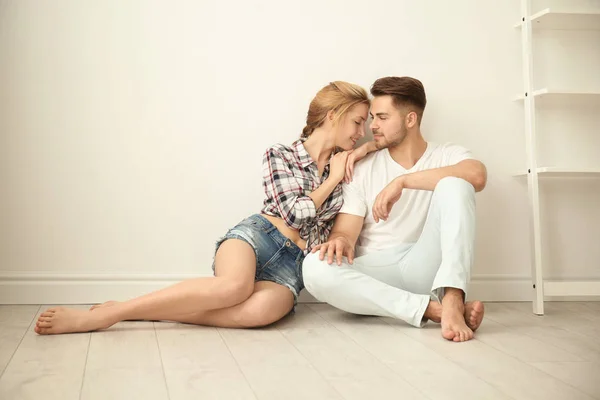 Lykkelige unge par sidder på gulvet derhjemme - Stock-foto
