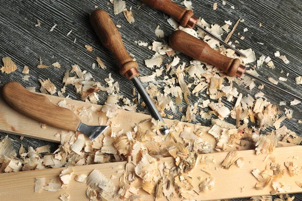 Conjunto de ferramentas, tábuas de madeira e pó de serra na mesa da oficina de carpinteiro — Fotografia de Stock