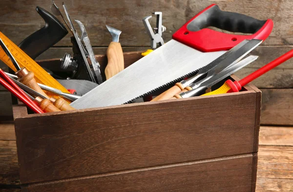 Låda med snickarens verktyg på bordet mot trä bakgrund, närbild — Stockfoto