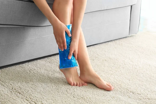 Młoda kobieta stosowanie zimny kompres do nóg w domu — Zdjęcie stockowe