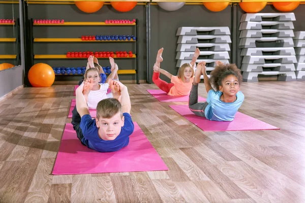 Los niños en la lección de educación física en el gimnasio escolar —  Fotos de Stock