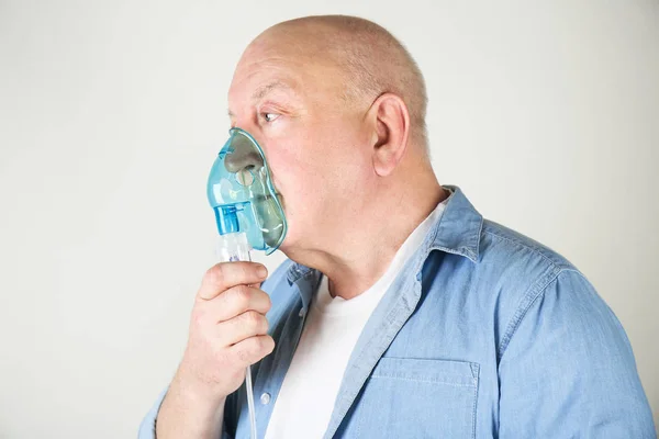 Hombre mayor usando máquina de asma sobre fondo claro — Foto de Stock