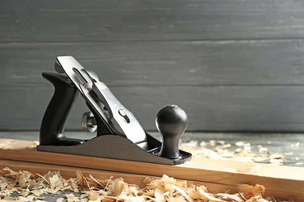 Bench plane, wooden boards and saw dust on table in carpenter's workshop — Stock Photo, Image