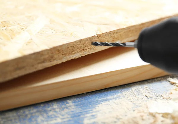 Furo de perfuração em placa de madeira na oficina de carpinteiro, close-up — Fotografia de Stock