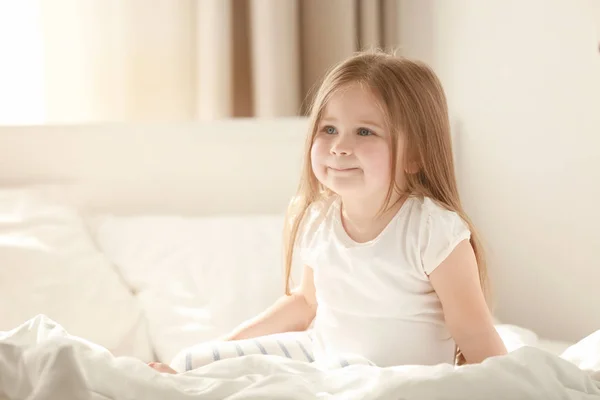 Симпатична маленька дівчинка сидить на ліжку — стокове фото