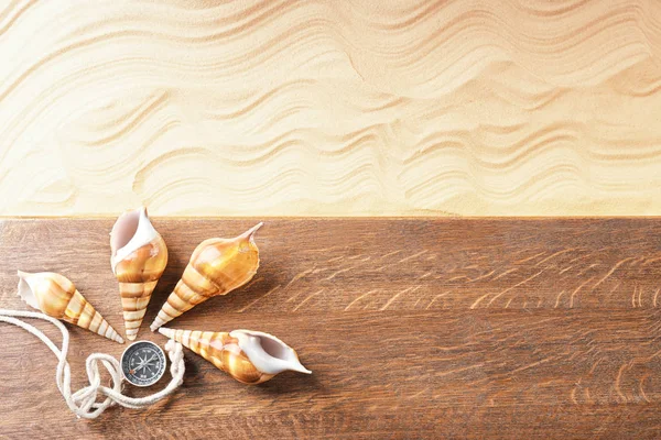 Samenstelling met houten plank, zeeschelpen en kompas op zand. Concept van reizen en vakantie — Stockfoto