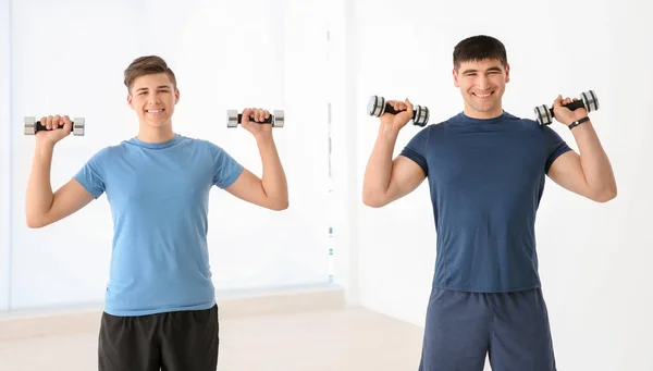 Pappa och son träning med hantlar i gymmet — Stockfoto