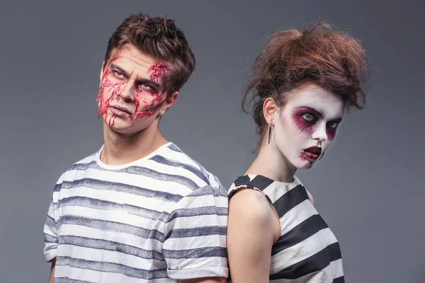 Mladý muž a žena s makeupem Halloween na šedém pozadí — Stock fotografie