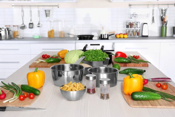 Свежие овощи и посуда для уроков кулинарии на деревянном столе — стоковое фото