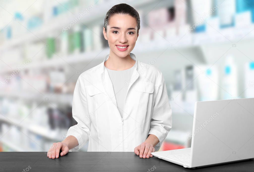 Young female pharmacist near counter  