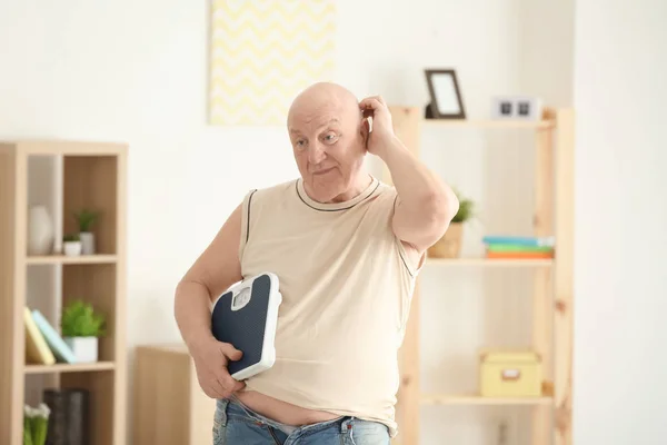 Gros sénior avec des écailles à la maison. Concept de perte de poids — Photo