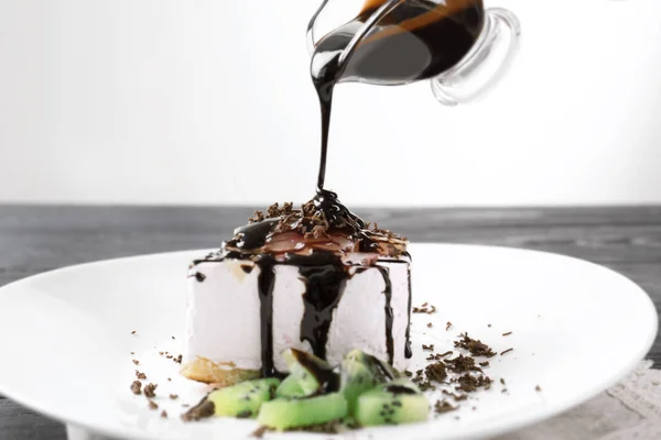 Despeje molho de chocolate no prato com bolo saboroso — Fotografia de Stock