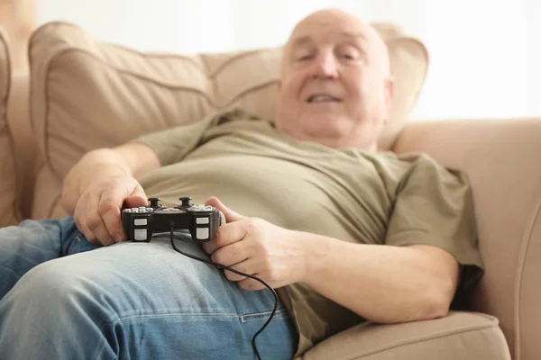 Gruby mężczyzna senior grając gier wideo, leżąc na kanapie w domu, zbliżenie. Koncepcja siedzący tryb życia — Zdjęcie stockowe