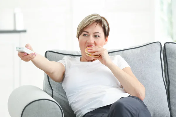 Wanita menonton TV dan makan hamburger — Stok Foto