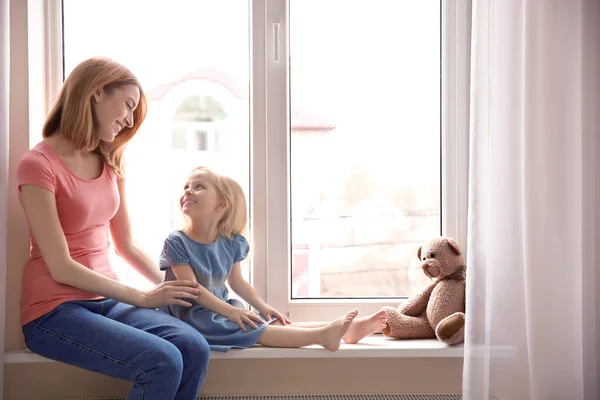 Mother and daughter on windowsill — Stock Photo, Image