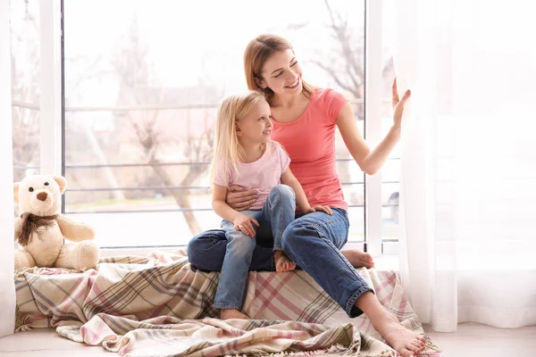 Madre e hija en alféizar de la ventana —  Fotos de Stock