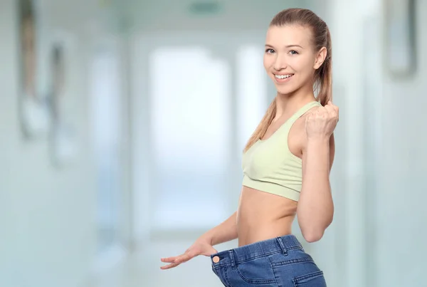 Gewichtsconcept verlies. Jonge vrouw in grote maten jeans op onscherpe achtergrond — Stockfoto