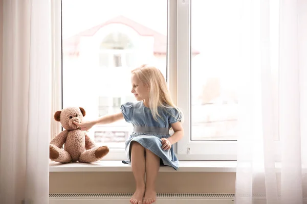 Schattig klein meisje zittend op de vensterbank — Stockfoto