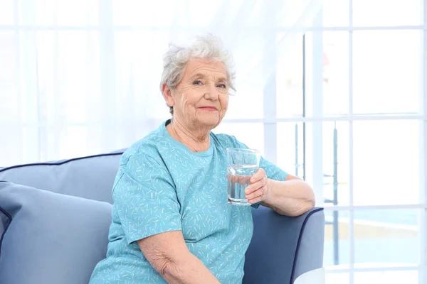 Пожилая женщина держит стакан воды — стоковое фото