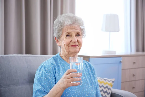 Пожилая женщина держит стакан воды — стоковое фото