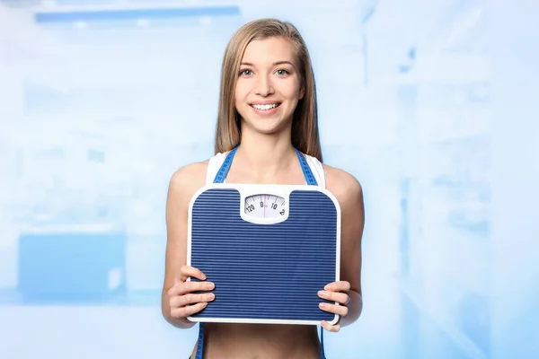 Concepto de pérdida de peso. Mujer joven con escamas y cinta métrica sobre fondo borroso — Foto de Stock