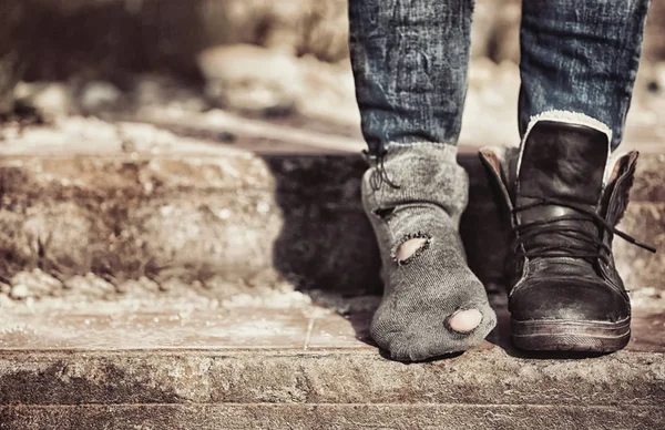 Poverty concept. Poor woman wearing tatter sock and one boot — Stock Photo, Image
