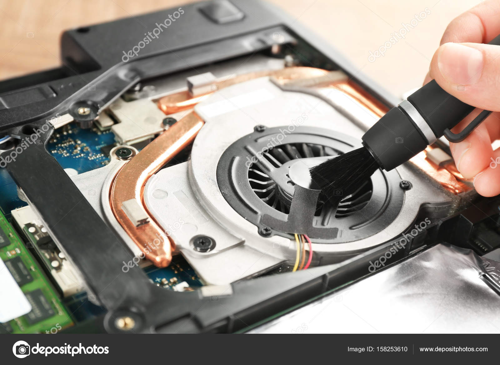 Man cleaning laptop cooler with brush Stock Photo by ©belchonock 158253610