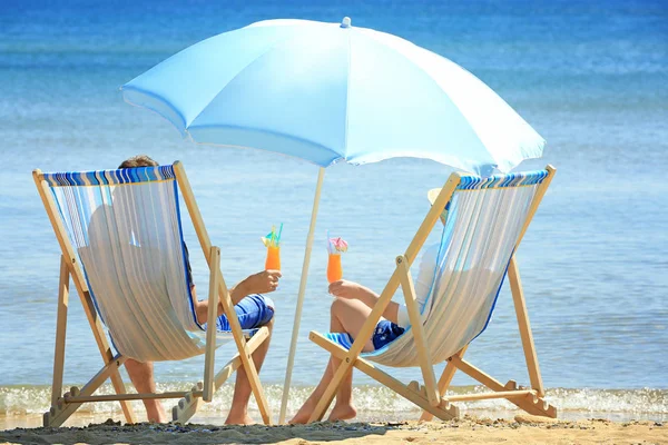 Pasangan dengan koktail duduk di kursi pantai — Stok Foto