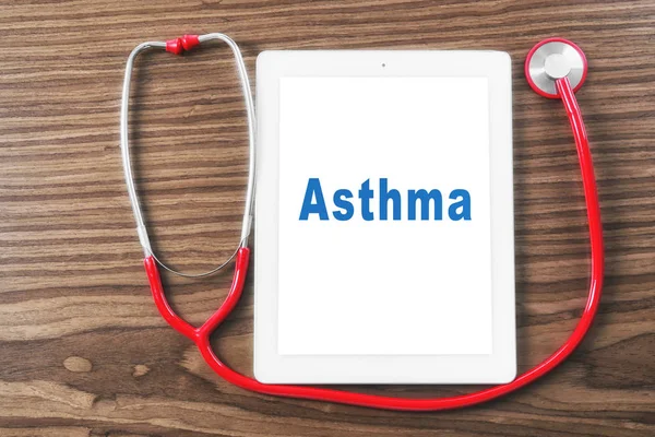Concepto de salud. Estetoscopio y tableta con palabra ASMA en pantalla, fondo de madera — Foto de Stock