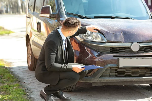 Loss adjuster inspecting car — Stock Photo, Image