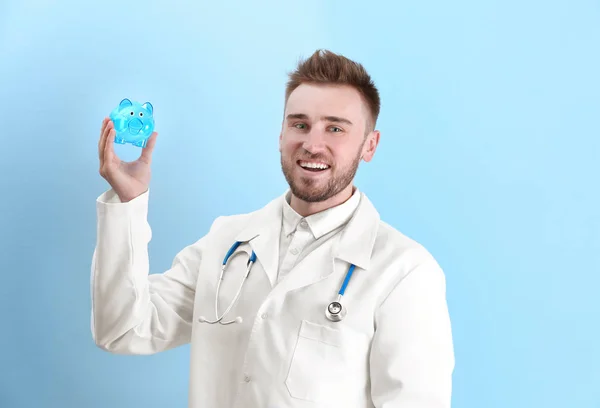 Young doctor holding piggy bank — Stock Photo, Image