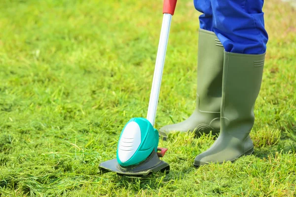 Arbetare som klipper gräsmattan med grästrimmer — Stockfoto